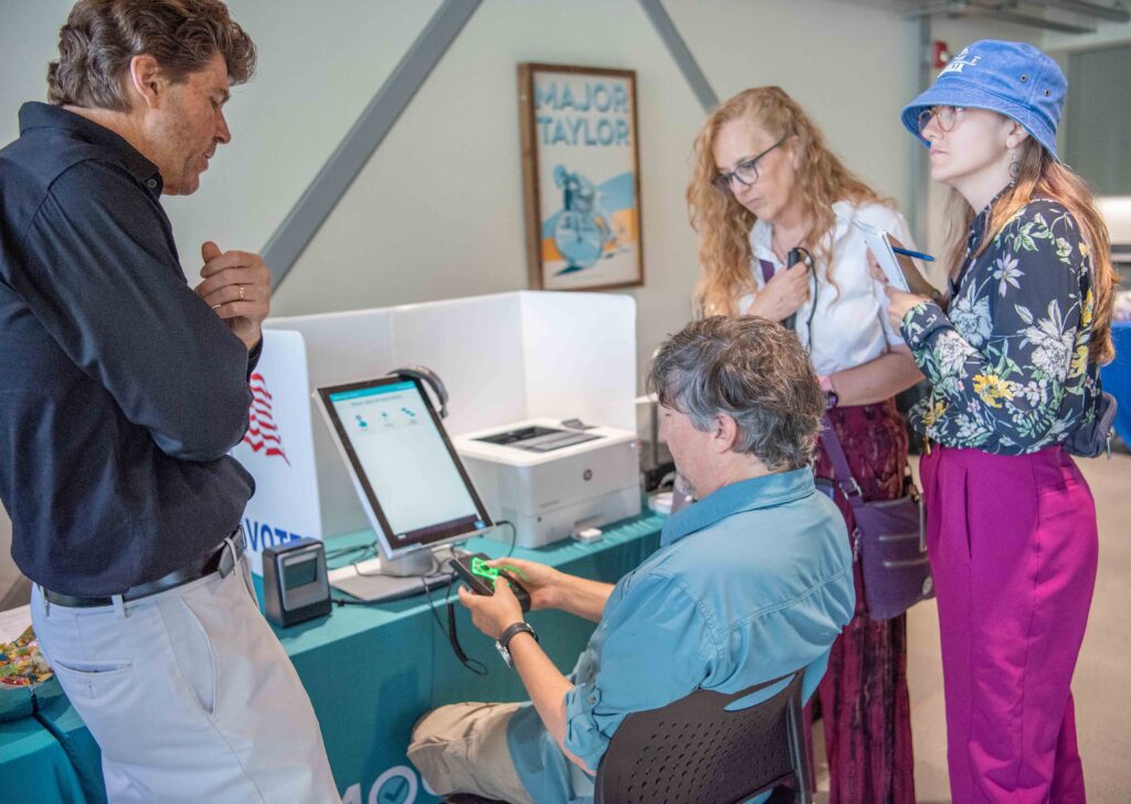 An attendee tries out Democracy Live with friends looking on